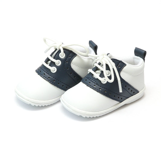 The Austin has stayed true to the look of the traditional saddle shoe, over many years. This is a true classic. With white leather exterior and contrasting leather saddle, Austin is a style that will make your little gent or little lady look absolutely proper!  Leather upper Functional lace up front Perforated trim at sides Pull tab at back for easy on/off