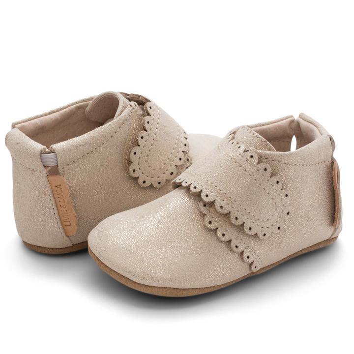 A darling and easily matchable boot for baby, Fleur offers a single hook-and-loop closure that make for easy on and off.  Stage: crawling Suede shimmer upper Natural leather lining Adjustable hook and loop closure for a tailored fit Padded elastic collar for easy on and off Tan suede sole with black recycled rubber tread circles Best suited for indoor use and light outdoor activity APMA approved sole