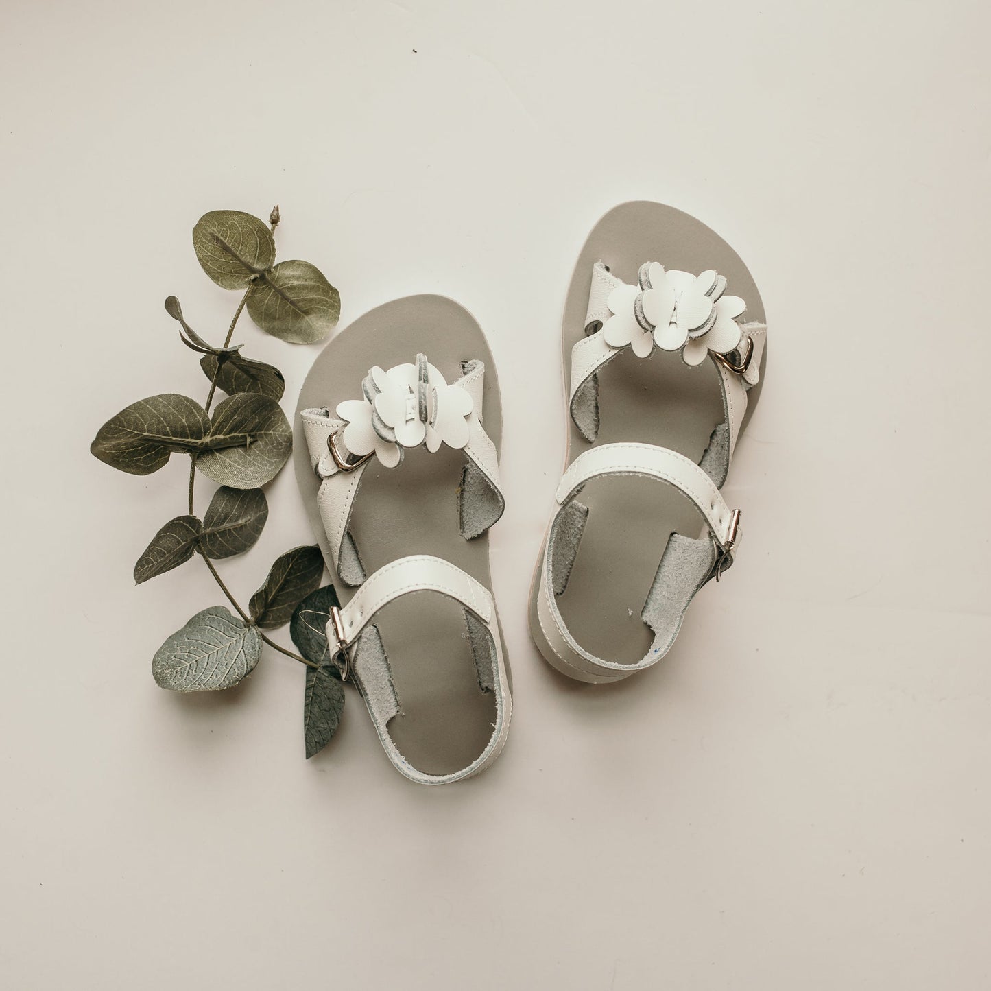 Each pair of shoes is carefully crafted in Central Pennsylvania.  The White Amelia Sandal is made of white leather and lined with breathable leather and cotton which work together to draw out any moisture. The structure of the shoe and the flexible sole provide stability without weight to support your child's early steps.